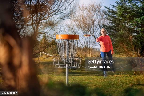 mujer poniendo durante un juego de golf disco - lanzar actividad física fotografías e imágenes de stock