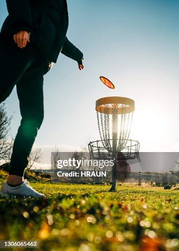Woman tossing a disc into the basket goal Woman tossing a disc into the basket goal