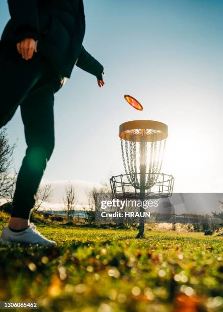 woman tossing a disc into the basket goal - disk stock pictures, royalty-free photos & images