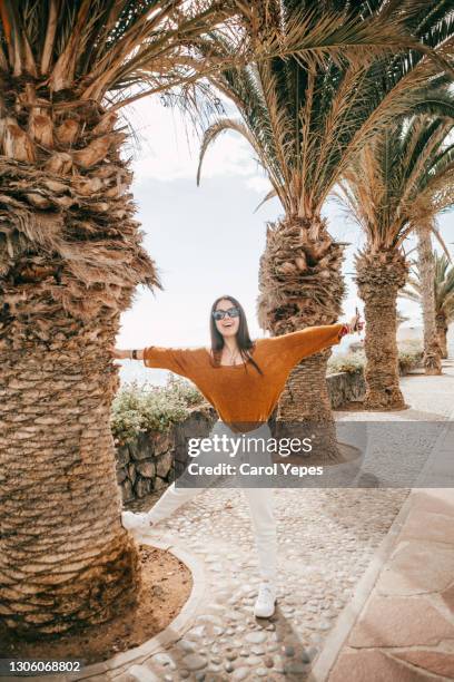 young latina posing with joy expression in a beautiful tree palm street in tenerife islands,spain - hot latino girl stock pictures, royalty-free photos & images