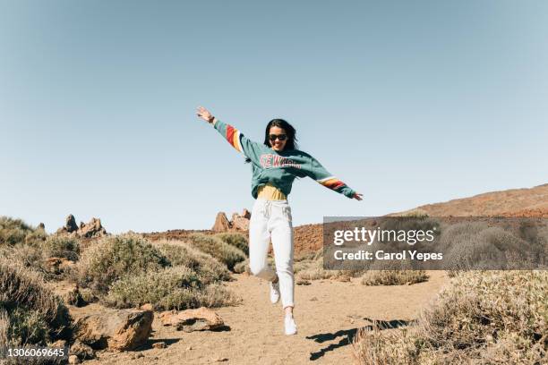 cheerful female teenager in sport clothes  jumping for  joy in a rural country wild landscape - woman travel stock-fotos und bilder