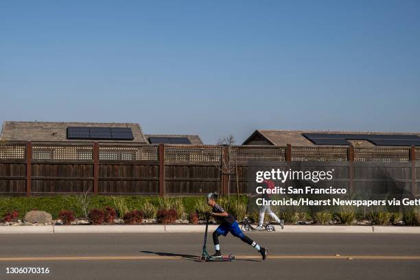 Two teenagers ride scooters along Dell'Osso Drive at the planned community at River Islands in Lathrop, California Thursday, Mar. 4, 2021. The...