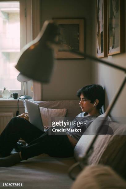 pre-adolescent boy e-learning on laptop while sitting in bedroom - pre adolescent child bildbanksfoton och bilder