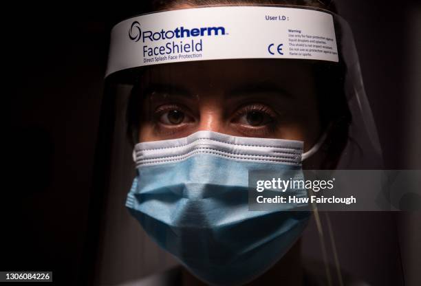 Auxiliary Nurse Jade Vicarage poses for a photograph wearing a face mask and visor at Nevill Hospital on March 08, 2021 in Abergavenny, Wales. The...