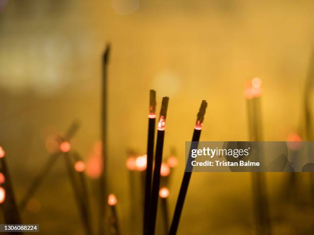 one hundred incense sticks smoulder at a sri lankan temple emitting an orange glow of light - incense stock pictures, royalty-free photos & images