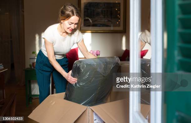 woman unpacking a new piece of furniture - furniture stock-fotos und bilder