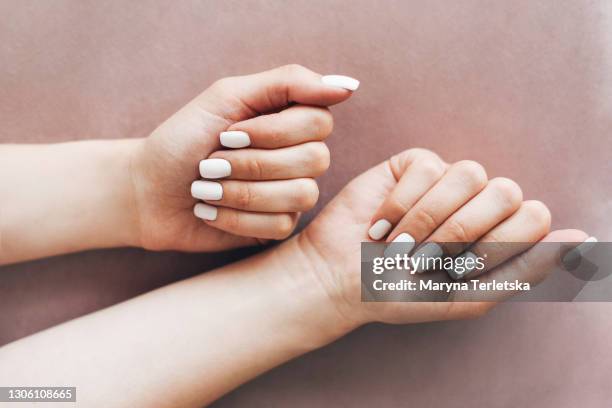 female hands with a neat white manicure on a beige background. - gel de cabelo imagens e fotografias de stock