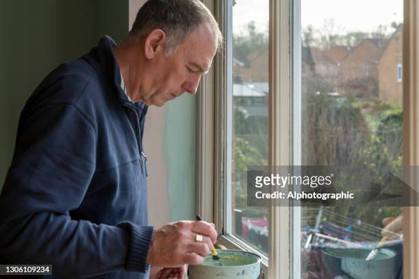 senior man painting an internal wall - january 2021 stock pictures, royalty-free photos & images