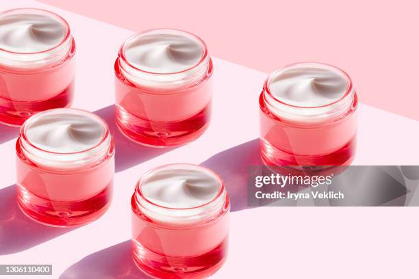 trendy pattern made of beauty product cream in pink color bottle on pastel pink background. - cosmetica fotografías e imágenes de stock