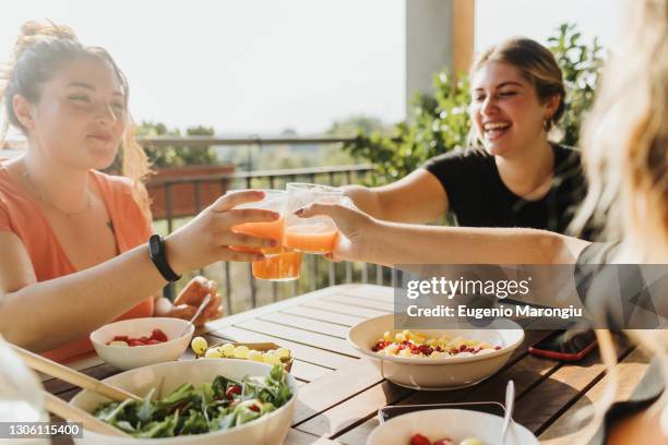 friends toasting with glasses of juice - buxom women ストックフォトと画像