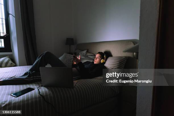 young woman using mobile phone in bed - addiction mobile and laptop stockfoto's en -beelden