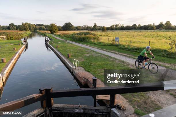 man cycling beside canal lock - kanaalsluis stockfoto's en -beelden