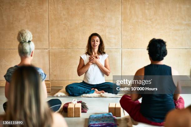 yoga instructor with hands clasped teaching class - yogalehrer stock-fotos und bilder