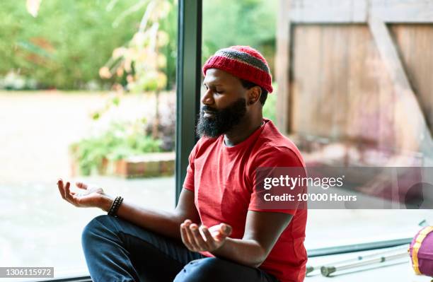 mature man wearing hat meditating in yoga class - introspection - fotografias e filmes do acervo