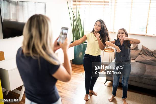 mother filming teenager daughters dancing at home - mother media call stock pictures, royalty-free photos & images