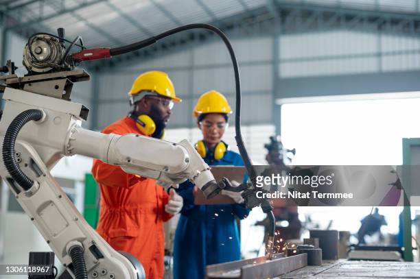 group of diversity engineer having a meeting over industrial robots welder in a factory. engineer controlling robotic welder in automotive production line of factory. - cam imagens e fotografias de stock