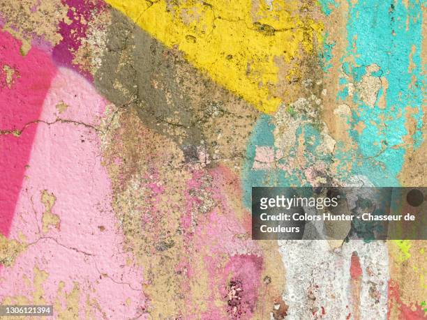 cracked and textured concrete wall with weathered paints in paris - graffiti wall stock-fotos und bilder
