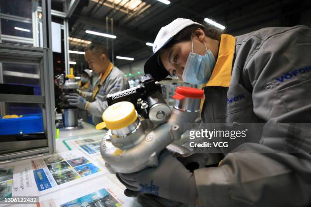 Employees work on the assembly line of turbochargers for automobiles at a factory of Vofon Turbo System Co., Ltd on March 9, 2021 in Jiaxing,...