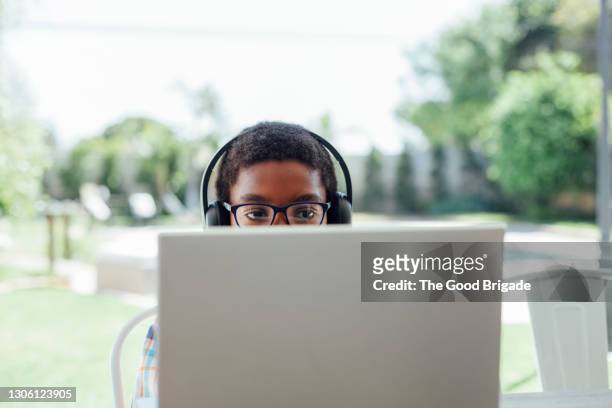 boy with headphones using laptop in backyard - summer school imagens e fotografias de stock