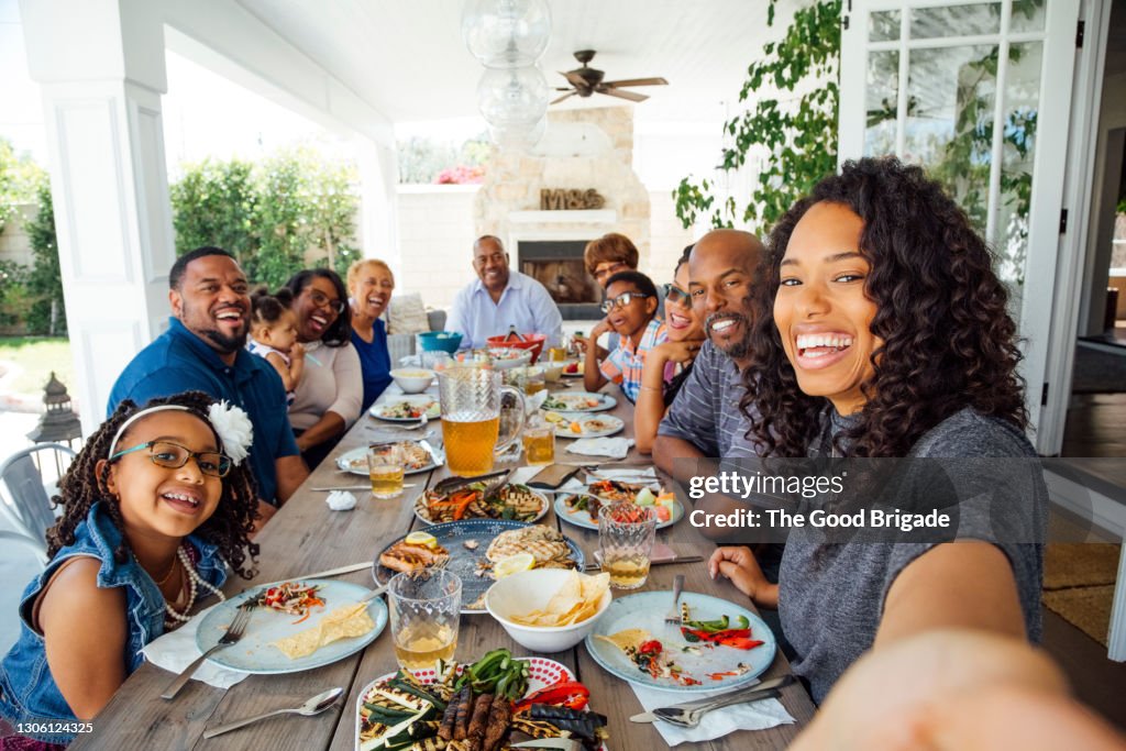 Smiling woman taking selfie with family at dinner party