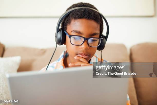 boy with headphones using laptop in living room - child listening differential focus stock pictures, royalty-free photos & images