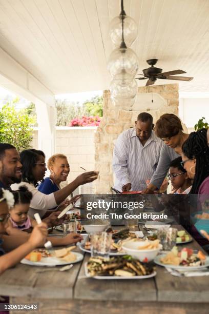 happy family enjoying meal together on patio during summer - multi generation family summer stock pictures, royalty-free photos & images