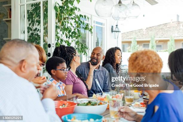 happy family enjoying food at table during party - familientreffen stock-fotos und bilder