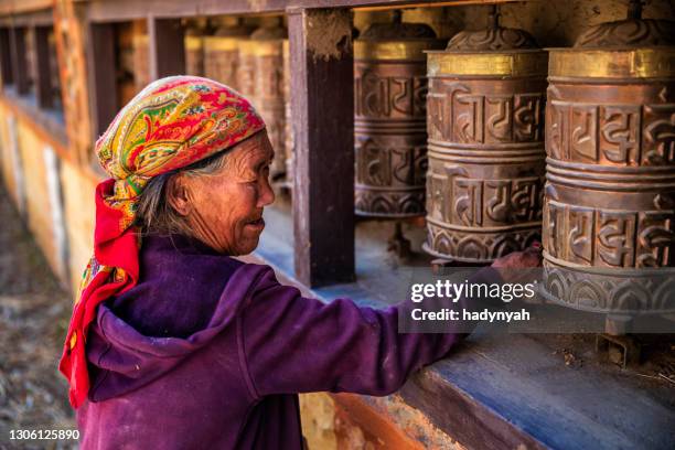 old tibetan woman turning the prayer wheels, upper mustang - nepal road stock pictures, royalty-free photos & images