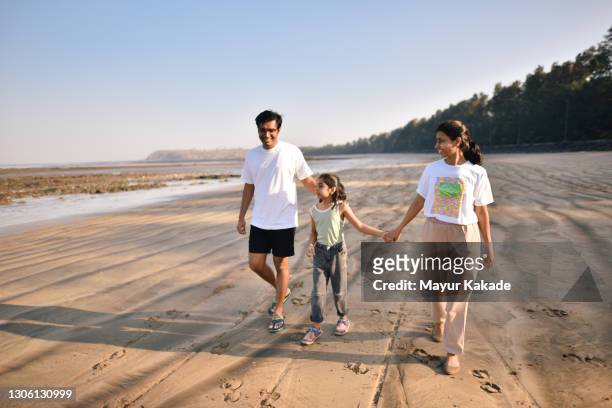 family walking together on the beach - indian family stock pictures, royalty-free photos & images