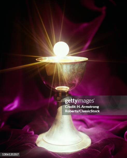 1960s Christian Holy Communion Cup Chalice And Eucharist Wafer With star Burst Effect On Purple Velvet Background .