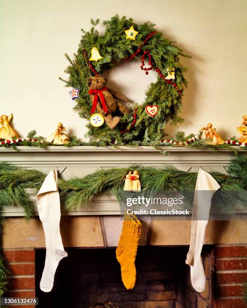 1980s Christmas Fireplace Mantle Decorated With Homespun Hand Crafted Items Wreath Garland stockings Ornaments.