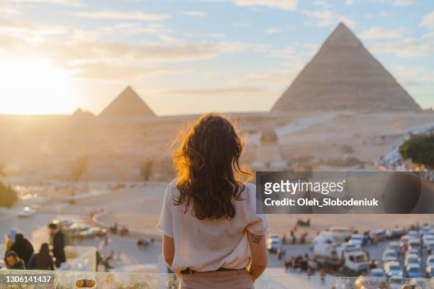frau steht auf der terrasse im hintergrund der pyramiden von gizeh - reise stock-fotos und bilder
