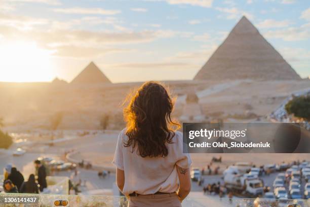 vrouw die zich op het terras op de achtergrond van de piramides van gizeh bevindt - egypte stockfoto's en -beelden