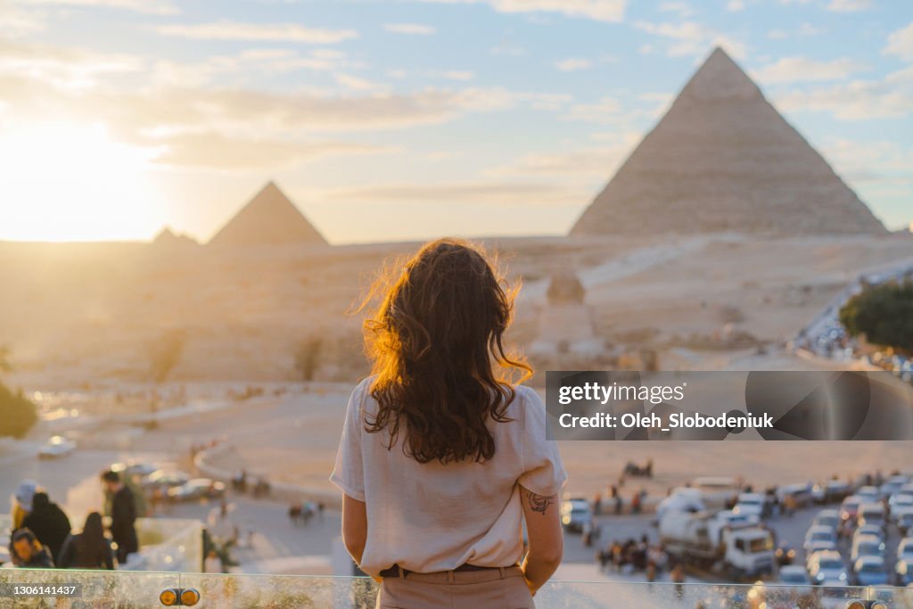 Woman standing on the terrace on the background of Giza pyramids