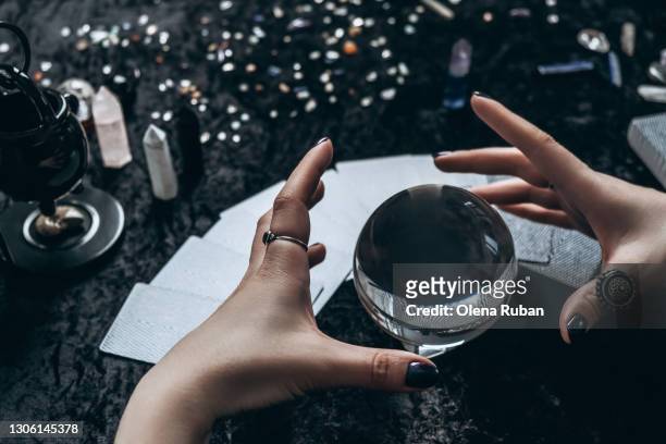 women's hands conjure around a transparent sphere - waarzeggerij stockfoto's en -beelden