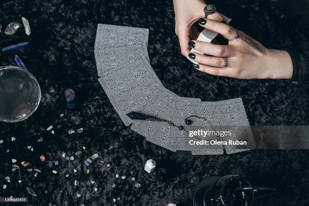 Young woman holding a deck of cards in front of laid out tarot cards