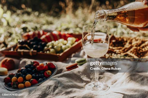 wine pouring from a bottle into glass on a picnic close-up - harvest table stock-fotos und bilder