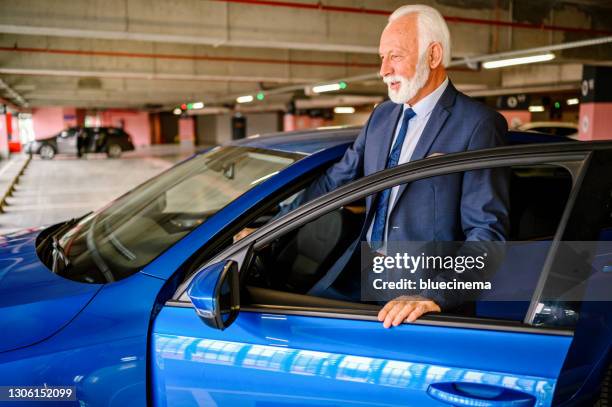 senior geschäftsmann in der garage entriegelt sein auto. - car alarm stock-fotos und bilder