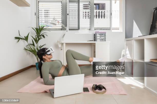 sportswoman doing exercises and experiencing virtual reality at home - vr goggles woman stock-fotos und bilder