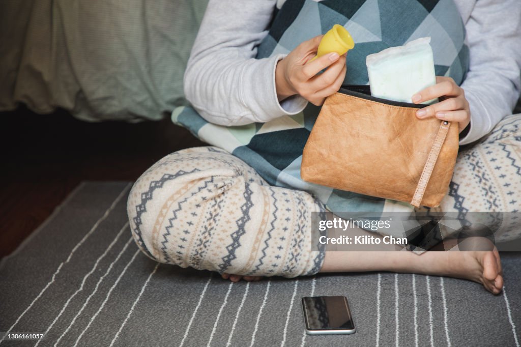Asian woman taking menstrual products out of a bag