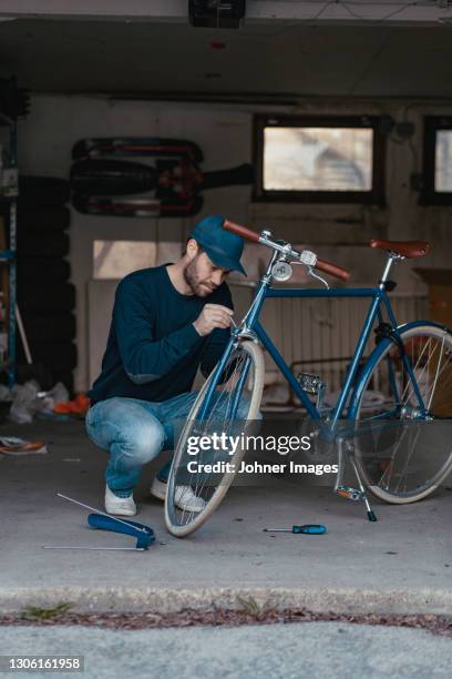 man repairing bicycle in garage - bicycle repair stock pictures, royalty-free photos & images