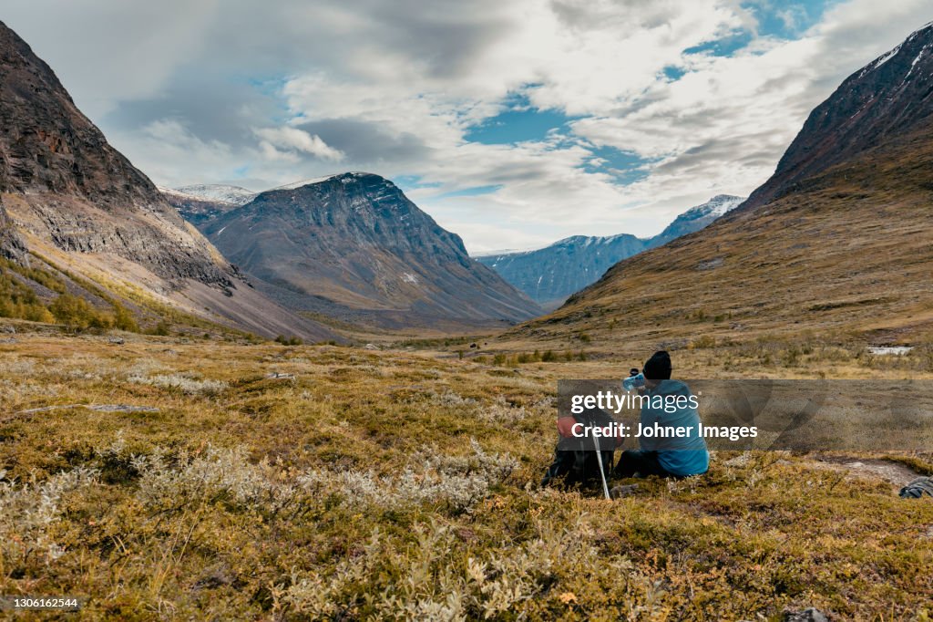 Rear view of hiker resting in mountains