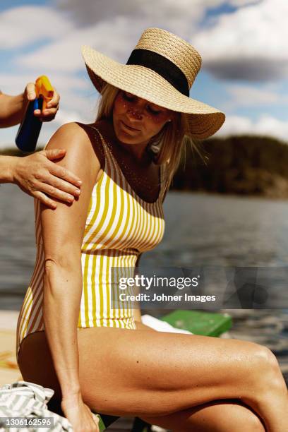 woman applying sun cream on friends back - spf 30 stock-fotos und bilder