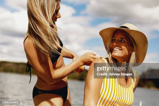 woman applying sun cream on friends back - bathing jetty stock pictures, royalty-free photos & images