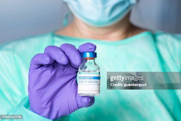 doctor holding a vial with covid-19 coronavirus vaccine - austria covid stock pictures, royalty-free photos & images