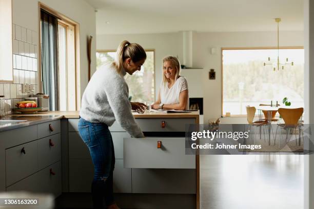 two women at kitchen counter - 引き出し ストックフォトと画像