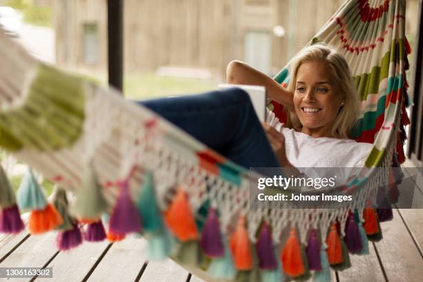 woman lying in hammock and using tablet - hammock imagens e fotografias de stock