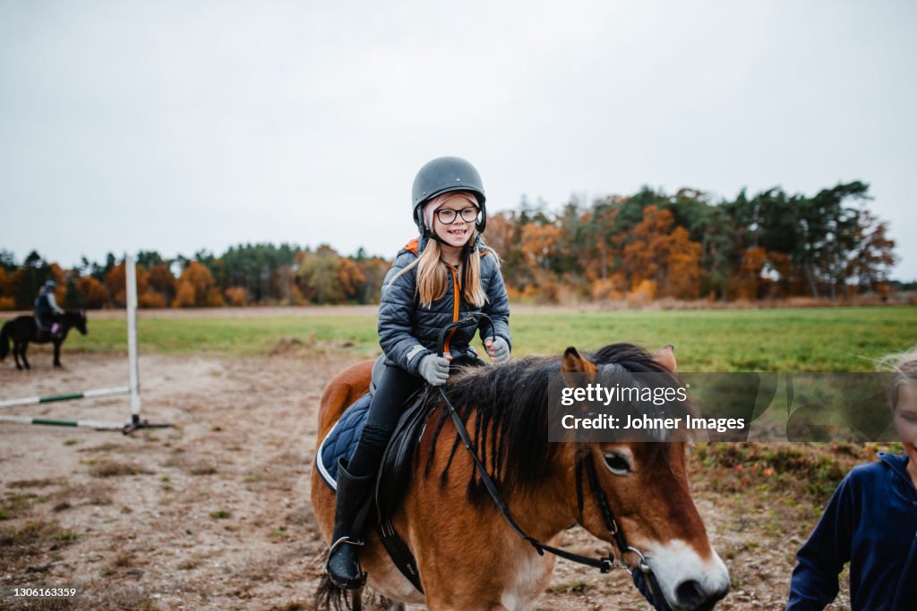Smiling girl riding pony