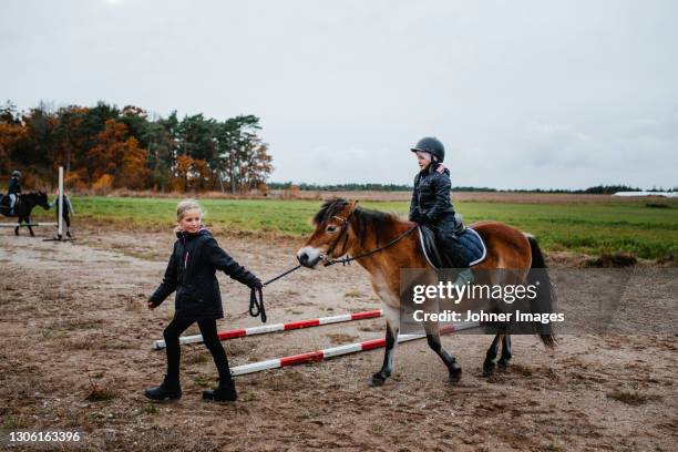 girl riding pony on paddock - pony paard stockfoto's en -beelden