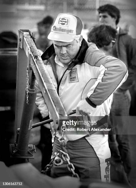 Racecar owner and legendary former driver Junior Johnson works on a racecar engine in the speedway garage prior to the start of the 1983 Daytona 500...